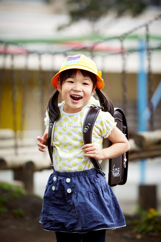 ランドセルと黄色い学生帽で笑顔の女の子