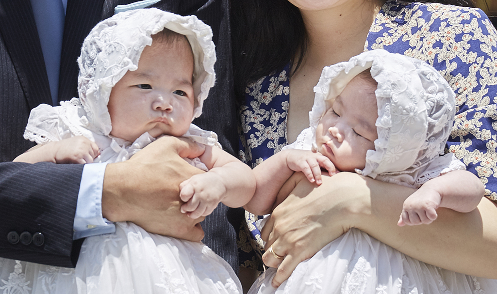 抱き抱えられる双子の赤ちゃん